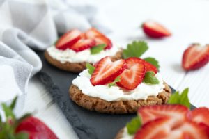 Healthy sandwich with strawberry and cream cheese on slate board.